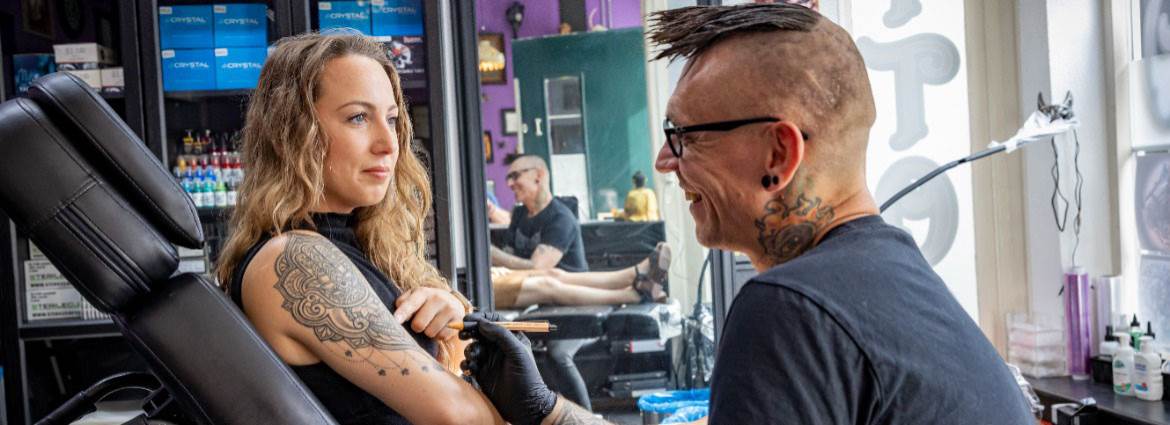 Vrouw laat tatoeage controleren bij tattoo shop